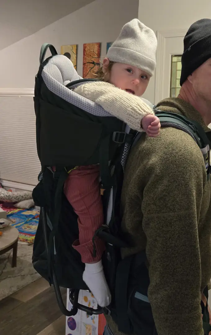 Charli riding comfortably in a backpack carrier.